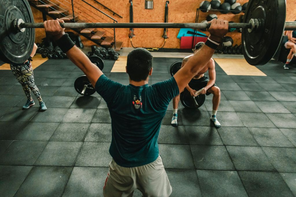 Current image: A group of men engaged in a vigorous weightlifting session at a gym.
